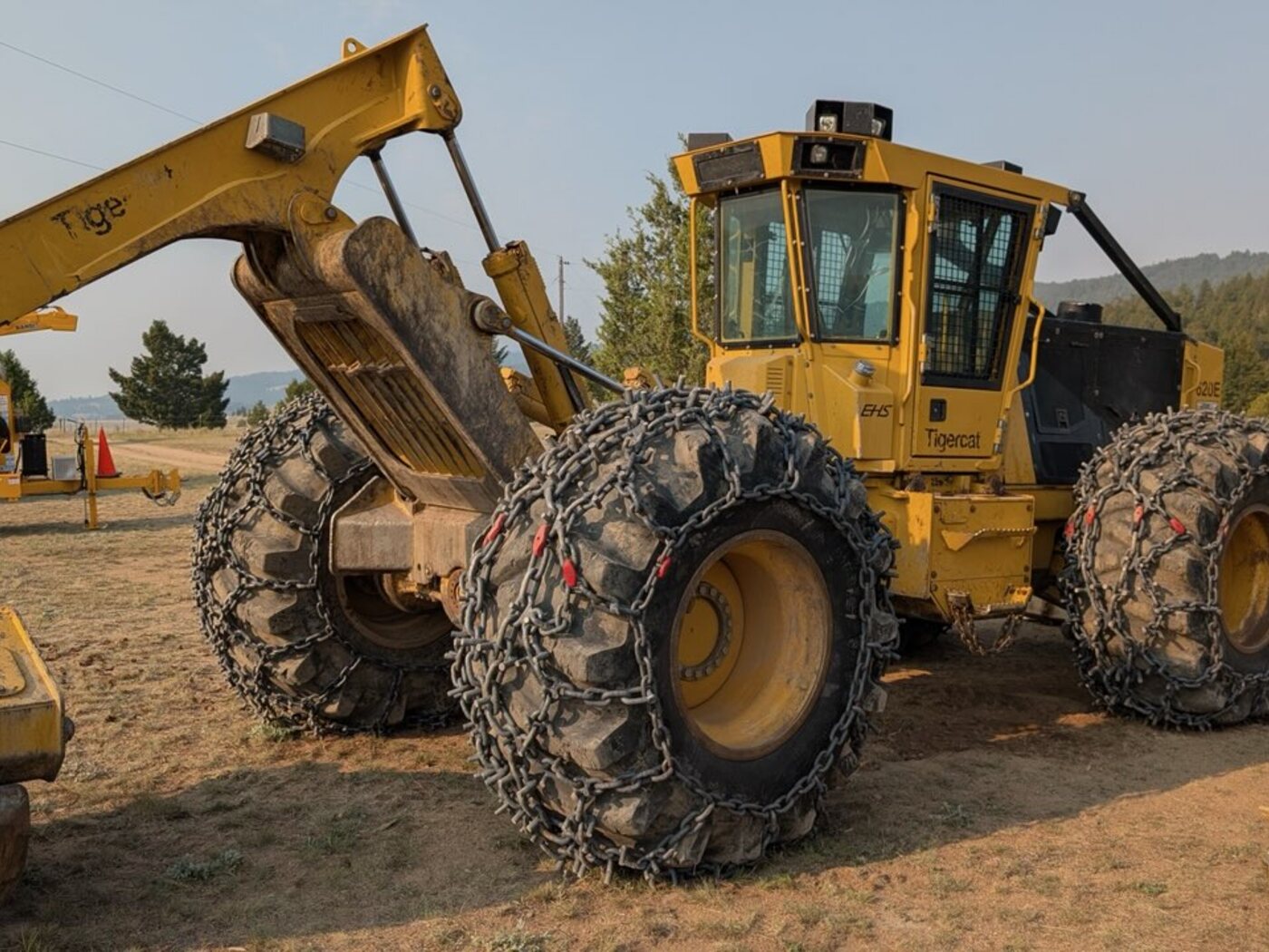 Tigercat 620E skidder blade and chained tires, front three-quarter view